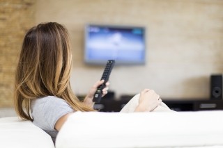 woman watching tv holding a remote