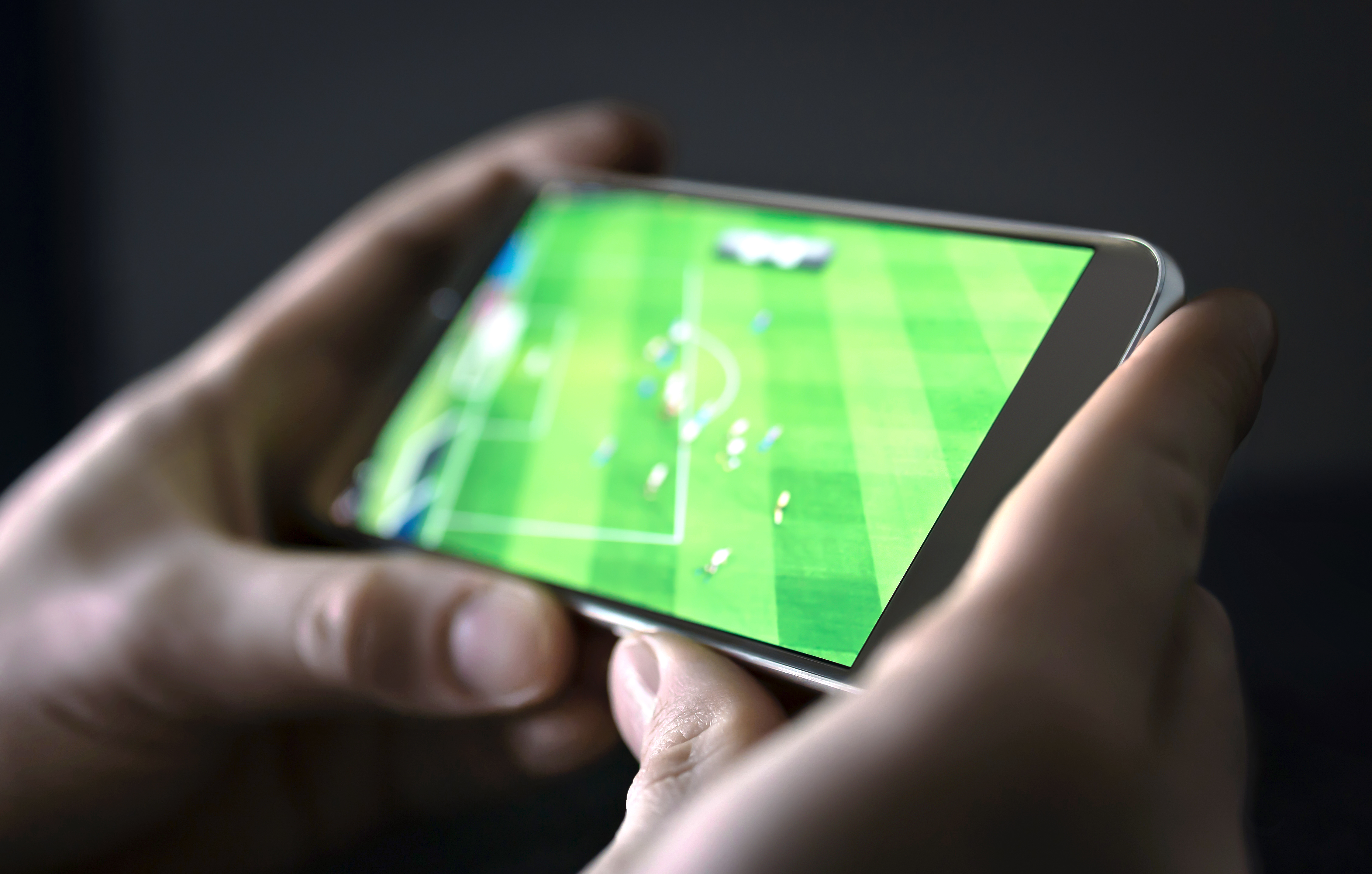 smartphone being held with soccer playing on the screen